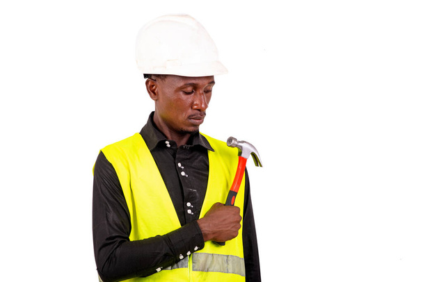 Jongeman technicus draagt groen vest en veiligheidshelm hamer. - Foto, afbeelding
