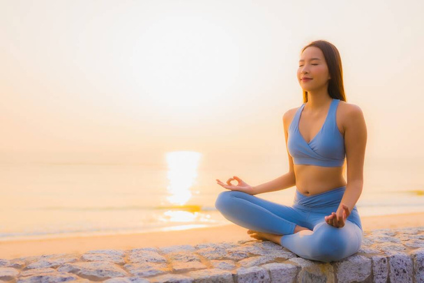 Porträt junge asiatische Frau meditieren rund um Meer Strand Ozean bei Sonnenaufgang für die Gesundheit - Foto, Bild