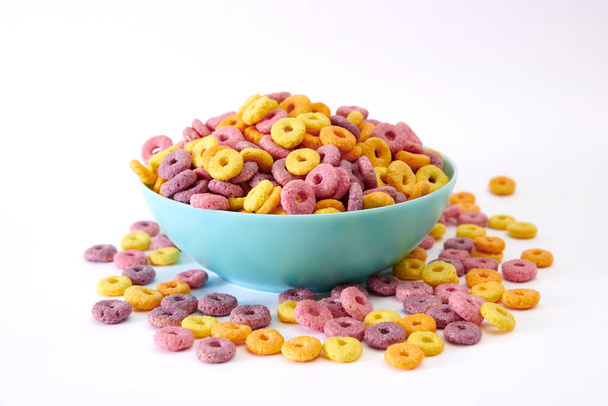 Un primo piano di multicolore cereali fruttati in una ciotola blu isolato su sfondo bianco - Foto, immagini