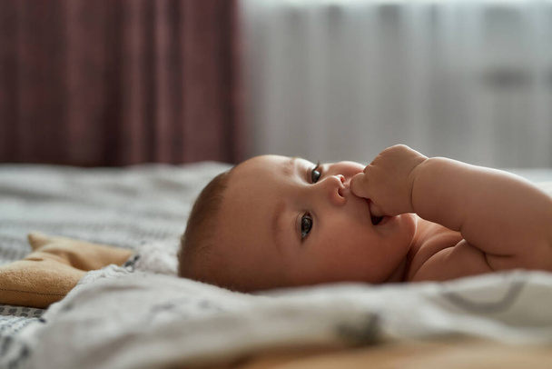 Teething infant baby holding fingers in mouth - Fotoğraf, Görsel