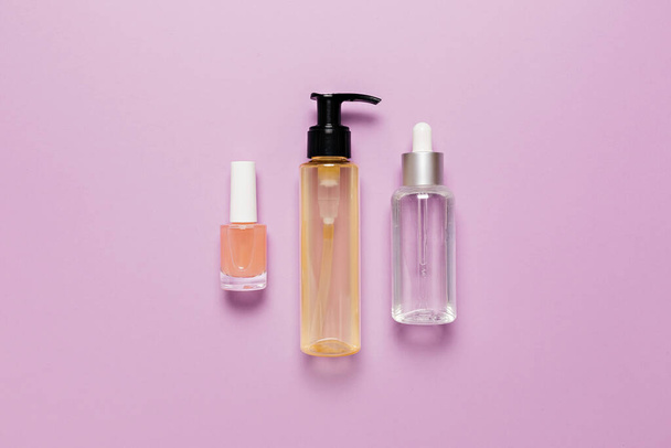 Organic cosmetics packaging design. Flat lay, top view clear glass pump bottle, brush jar, moisturizing serum jar on a purple background. Natural cosmetics SPA - Фото, зображення