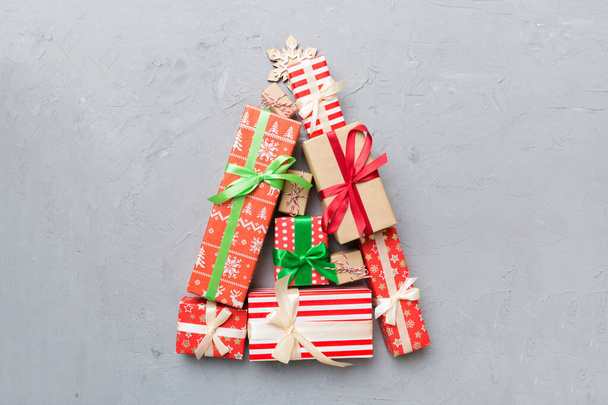 Christmas tree made of beautifuly wrapped presents on colored background, view from above. New Year gift box minimal concept with copy space. - 写真・画像