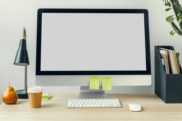 Computer monitor with mockup white screen on office table with supplies - 写真・画像