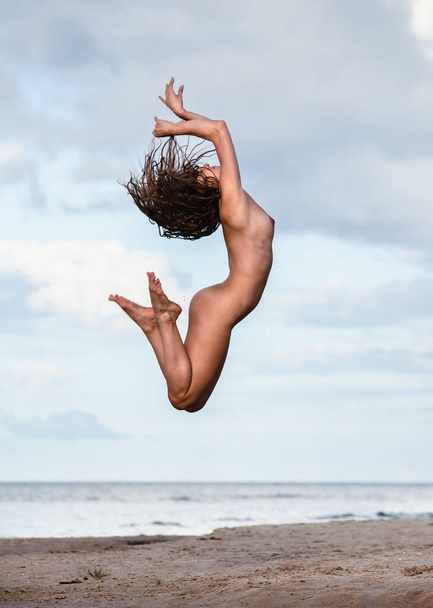 Γυμνή γυναίκα που πηδάει στην παραλία. Όμορφο κορίτσι σε εξωτερικούς χώρους απολαμβάνει τη φύση. Καλοκαιρινές δραστηριότητες και πτήσεις γυναικών. Έξτρα ευτυχία για ένα κορίτσι που πηδάει - Φωτογραφία, εικόνα