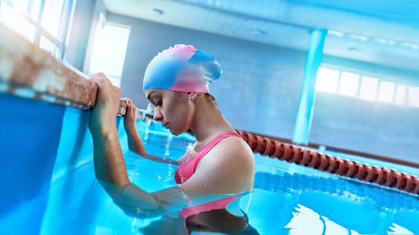 Fit athletic young woman swimmer in swimsuit and  swimming cap in sports pool during training - Φωτογραφία, εικόνα