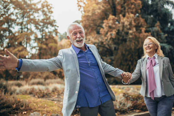 счастливая пожилая пара в осеннем парке - Фото, изображение