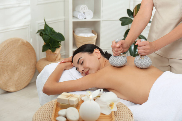 Young woman receiving herbal bag massage in spa salon - Foto, immagini