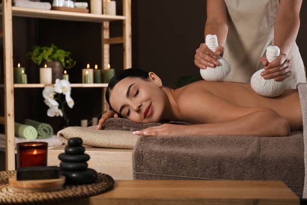 Young woman receiving herbal bag massage in spa salon - Foto, Imagem