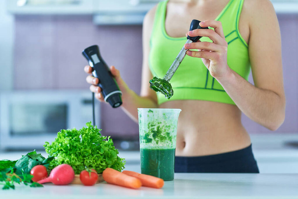 Diet fit woman using hand blender for cooking a green smoothie. Vegetables detox organic fitness drinks for healthy eating  - Foto, Bild