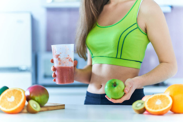 Fit woman in sportswear drinks a fresh fruit smoothie for losing weight. Vitamin diet drinks for healthy eating       - Zdjęcie, obraz