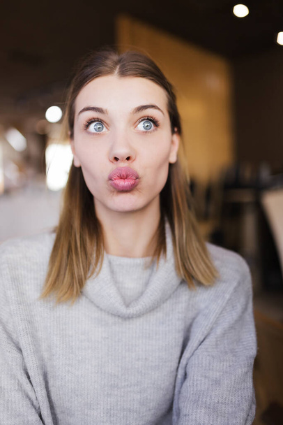 Portrait of a beautiful girl blowing a kiss in a cafe. - Foto, afbeelding