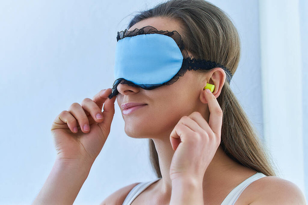 Young brunette woman using earplugs and eye mask for better sleeping and sweet dreams  - Photo, Image