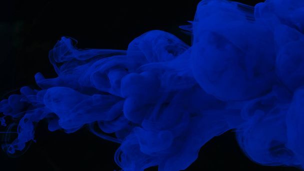 Blue watercolor paints in water on a black background. Awesome abstract background. Beautiful wallpaper for your desktop. Blue cloud of ink on a black background. Drops of blue ink in water. - 写真・画像