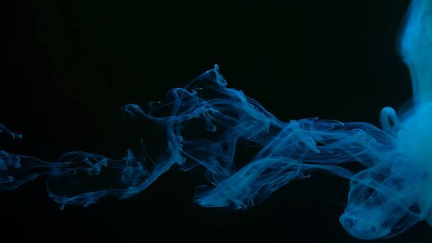 Awesome abstract background. Beautiful wallpaper for your desktop. Blue cloud of ink on a black background. Drops of blue ink in water. Blue watercolor paints in water on a black background. - Фото, изображение