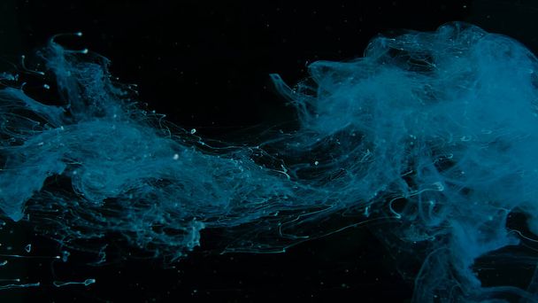 Blue watercolor paints in water on a black background. Awesome abstract background. Beautiful wallpaper for your desktop. Blue cloud of ink on a black background. Drops of blue ink in water. - Фото, изображение