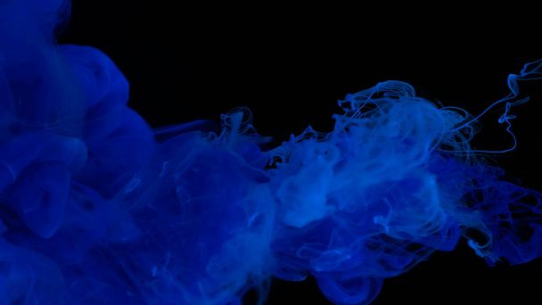 Blue watercolor paints in water on a black background. Awesome abstract background. Beautiful wallpaper for your desktop. Ultramarine cloud of ink on a black background. Drops of blue ultramarine ink in water. - Fotografie, Obrázek