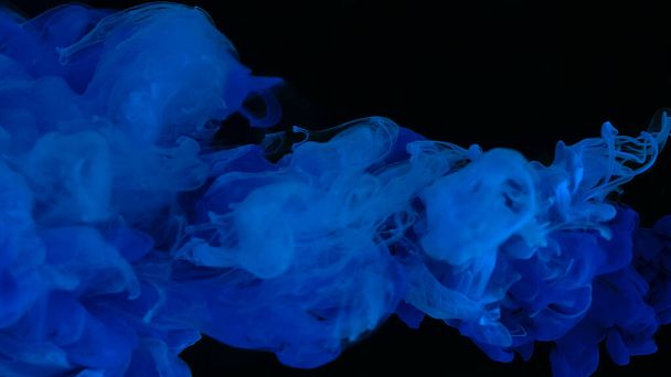 Beautiful wallpaper for your desktop. Ultramarine cloud of ink on a black background. Drops of blue ultramarine ink in water. Blue watercolor paints in water on a black background. Awesome abstract background. - Zdjęcie, obraz