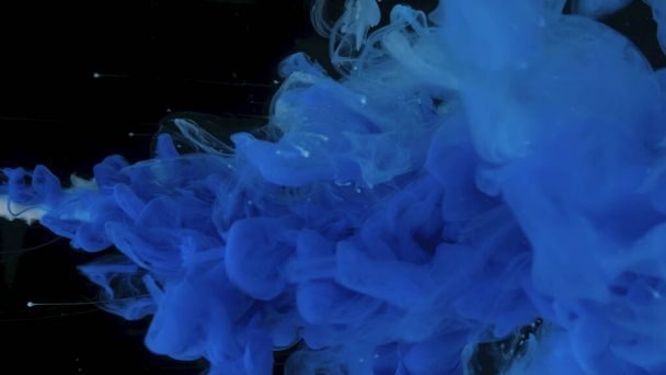 Blue cloud of ink on a black background. Drops of blue ink in water. Blue watercolor paints in water on a black background. Awesome abstract background. Beautiful wallpaper for your desktop. - Photo, image