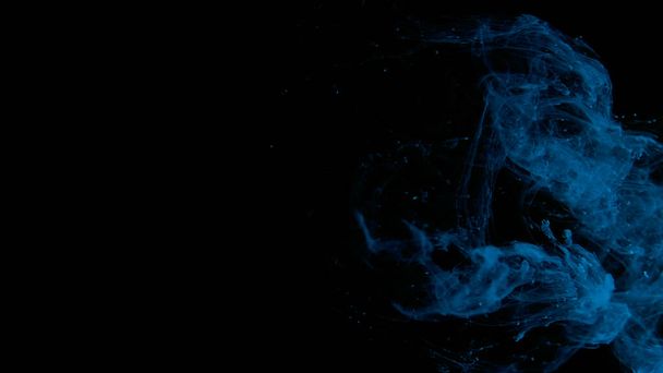 Blue cloud of ink on a black background. Drops of blue ink in water. Blue watercolor paints in water on a black background. Awesome abstract background. Beautiful wallpaper for your desktop. - Foto, Imagem
