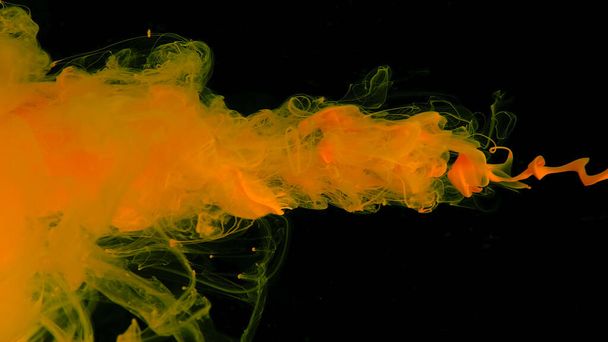 Yellow cloud of ink on a black background. Awesome abstract background. Yellow watercolor paints in water on a black background. Desktop wallpaper. - Zdjęcie, obraz