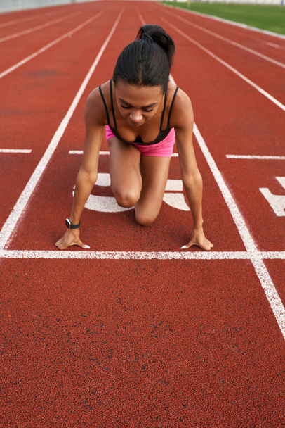 High angle view of professional young female runner in sportswear ready to race on track field at stadium - Foto, Imagem