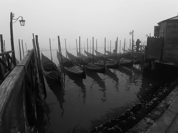 Венеция, Италия, 27 января 2020 г. Впечатляющее черно-белое изображение гондол, пришвартованных в канале - Фото, изображение