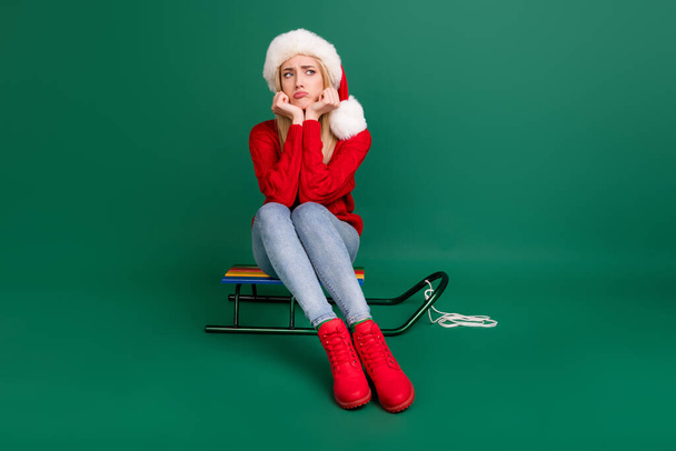 Full length body size photo grumpy woman sitting on wooden sledges isolated green color background - 写真・画像