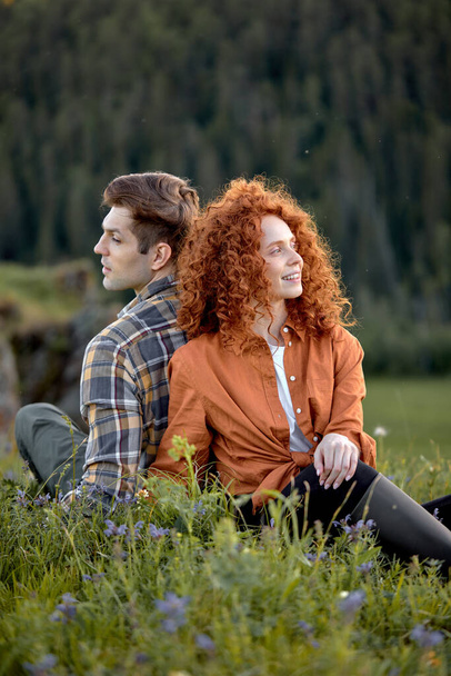 Side View Portrait Of Attractive Young Couple Sitting On Grass Together Relaxing - Photo, image