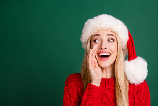 Photo of blonde young woman look empty space hand mouth tell news wear red sweater isolated on green color background - 写真・画像