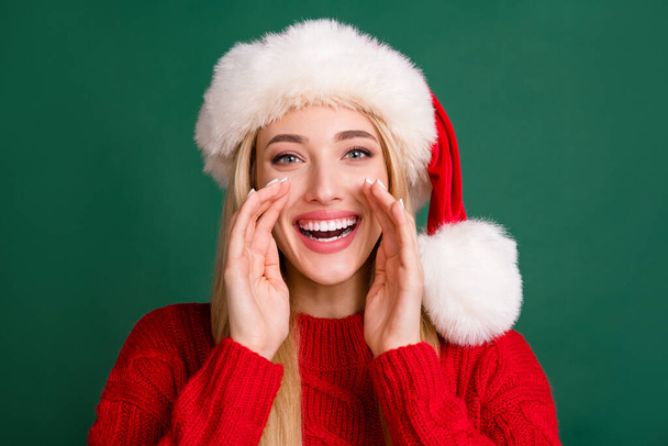 Photo portrait blonde woman in santa hat telling secret laughing isolated green color background - Photo, Image