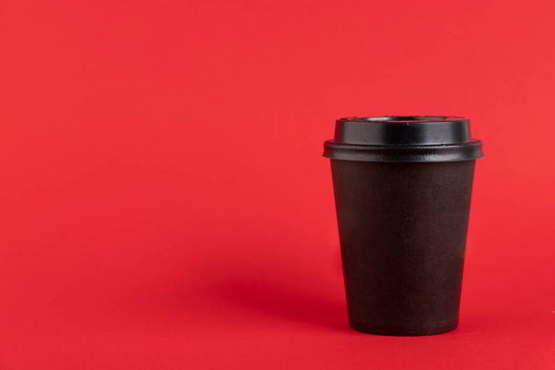 Black closed plastic, paper cup, for coffee or tea on a red background. Copy space. - Фото, зображення