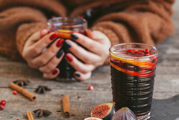 Womans hands in warm sweater holding a cup of mulled wine - Zdjęcie, obraz