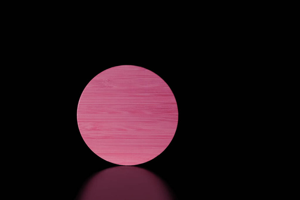 Close-up rosa redondo texturizado forma de madeira no fundo preto com refleção.Baixo key.Copy espaço para text.Product colocação room.Horizontal banner.Minimalism.Concept de supermoon ou sol na escuridão. - Foto, Imagem