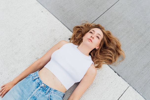 Young caucasian woman lying on the ground feeling sad and depressed - Foto, afbeelding