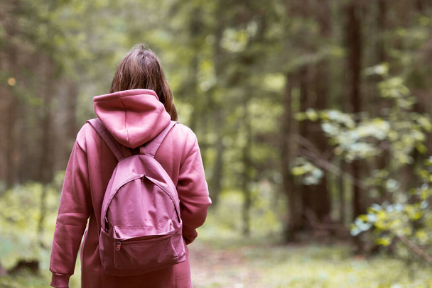 Mujer joven con capucha rosa caminando en el bosque de otoño - Foto, imagen