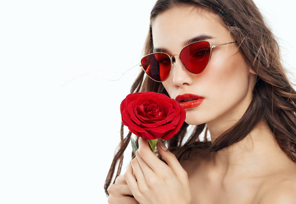 jolie femme en lunettes de soleil avec une rose dans les mains épaules nues - Photo, image