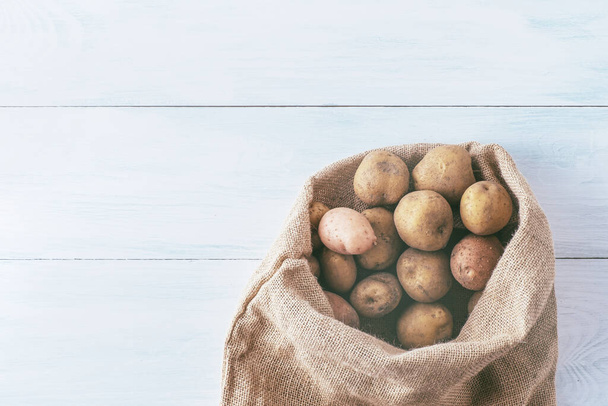 Fresh potatoes in a bag in a reusable package on a turquoise background. Package-free food shopping. Plastic free items. Reuse, reduce, refuse. Top view. High quality photo - Photo, Image