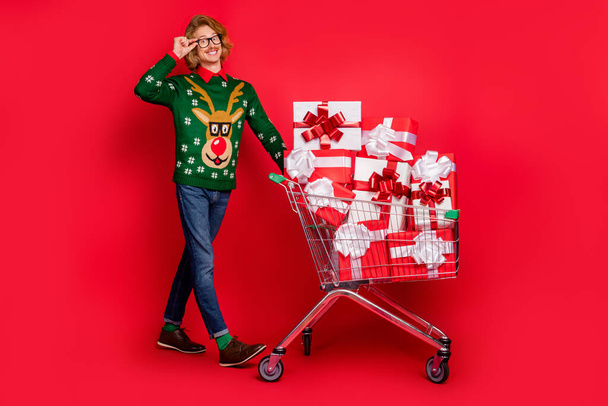 Full length body size view of attractive cheerful guy carrying cart going eve day isolated over bright red color background - Foto, imagen