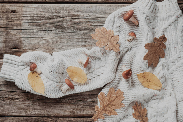 Modèle d'automne avec des feuilles et des champignons sur un pull tricoté. sur un fond en bois. Photo de haute qualité - Photo, image