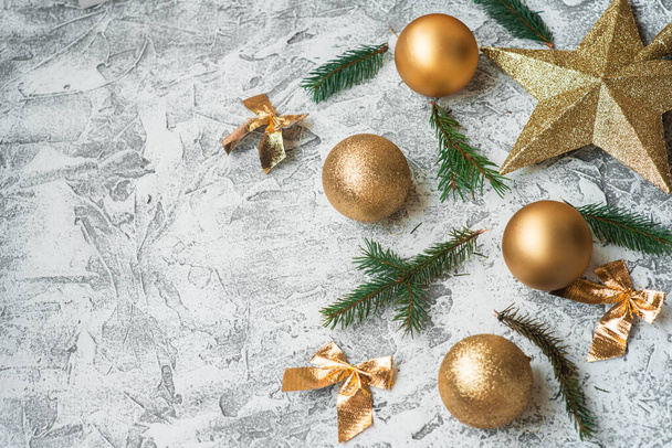 Nieuwjaars- of kerstcompositie van sparren groene takken en Nieuwjaars, glanzend gouden speelgoed en sterren op een heldere texturale achtergrond. Platte lay, lay-out, frame, plaats voor tekst, kopieerruimte, bovenaanzicht - Foto, afbeelding