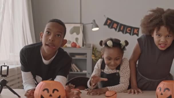 Slowmo tiro de quatro alunos afro-americanos em trajes de Halloween fazendo rostos assustadores imitando zumbis durante a festa de Halloween em casa - Filmagem, Vídeo