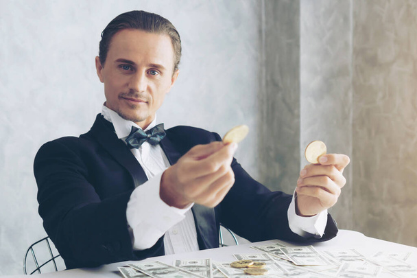 İş adamı zengini tüccar Bitcoin altın sikkesi tutuyor Bitcoin tüccarı için yeni para değişimi ve masa başı iş konsepti üzerine Amerikan doları banknotları - Fotoğraf, Görsel