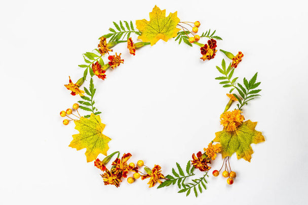 Autumn frame composition, isolated on a white background. A wreath from decorative fall leaves, berries, and marigold flowers - Photo, image