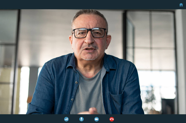 Senior man in gesprek met webcam - Foto, afbeelding