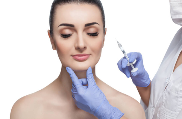 El médico cosmetólogo realiza el procedimiento de inyecciones faciales rejuvenecedoras para apretar y alisar las arrugas en la piel de la cara de una hermosa mujer joven en un salón de belleza.. - Foto, imagen