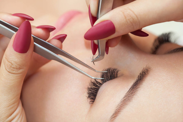 Eyelash removal procedure close up. Beautiful Woman with long lashes in a beauty salon. Eyelash extension. - Фото, зображення