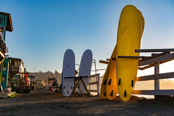 Білі та жовті дошки для серфінгу, що зберігаються в магазині на піщаному дні на пляжі в конконі (Чилі). - Фото, зображення