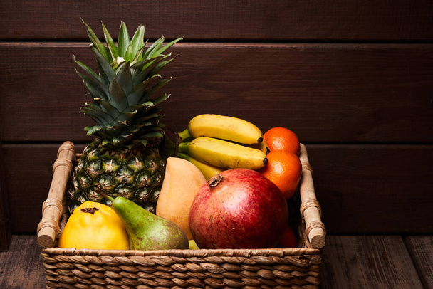 Mix of fresh juicy colorful exotic tropical fruits in basket on wooden background - Foto, Bild