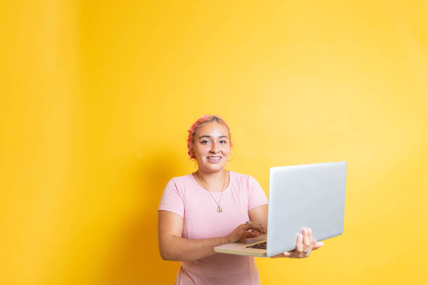 Mexican college student using laptop, on yellow isolated background. young hispanic latina - Fotó, kép