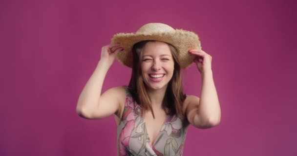 Gelukkig glimlachende vrouw neemt de strohoed af en gooit het weg met de lach, lachen jong model is op de geïsoleerde roze achtergrond, 4k Prores HQ 60fps - Video